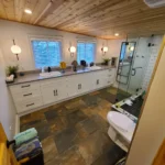 Rustic bathroom with wood ceiling and tiled floor.