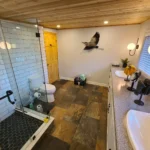 Modern bathroom with glass shower and dual sinks.