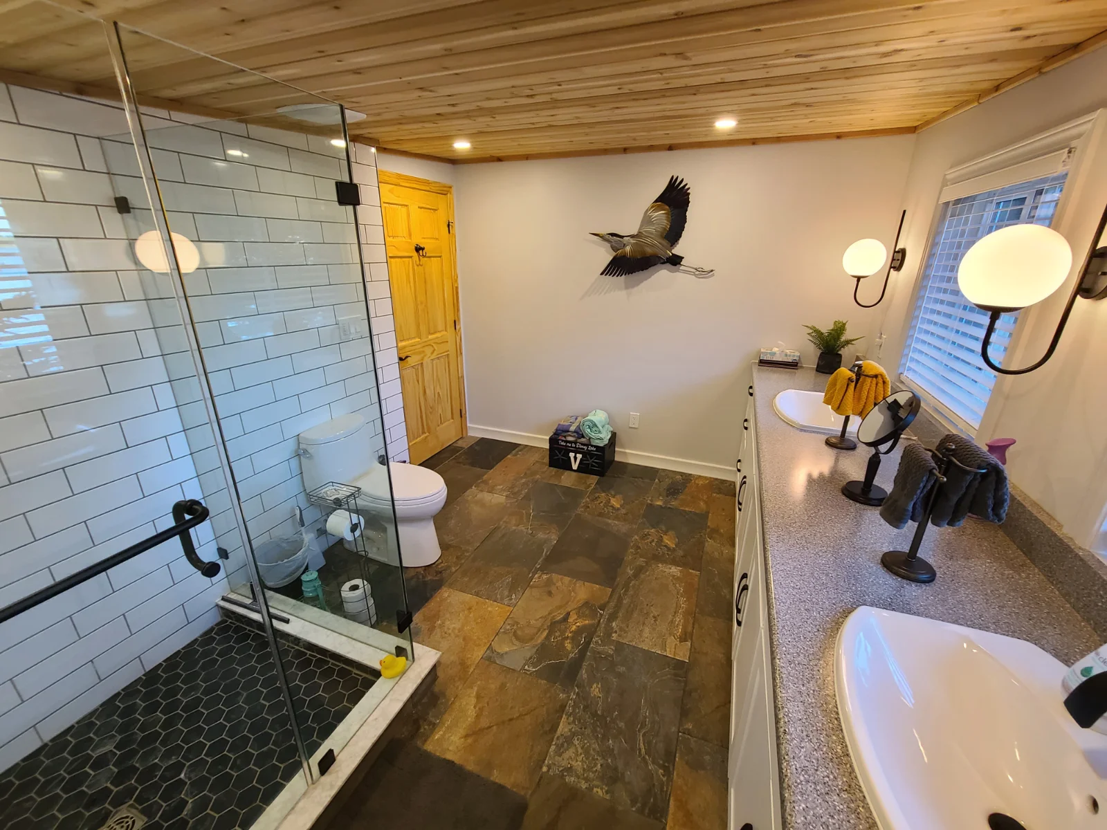 Modern bathroom with glass shower and dual sinks.