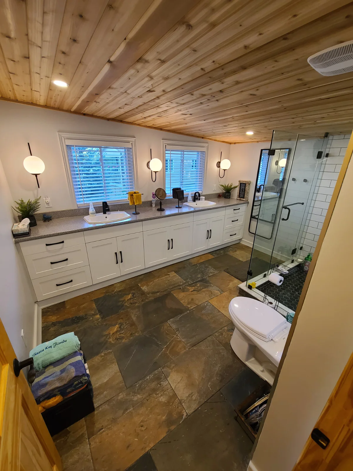 Rustic bathroom with wood ceiling and tiled floor.