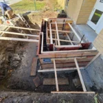 Construction site trench with wooden supports.