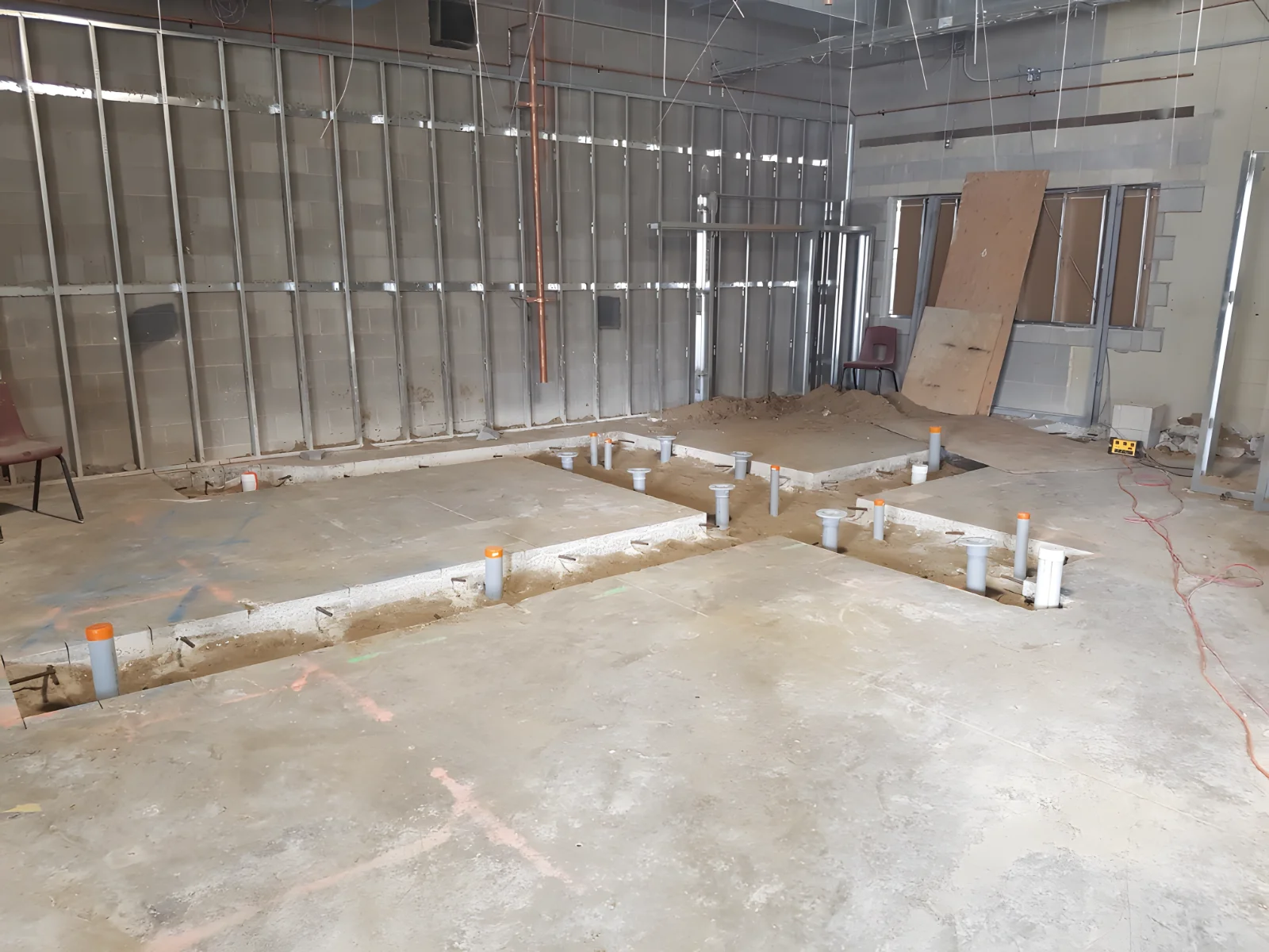 Construction site with exposed pipes and unfinished walls.