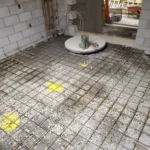 Construction site floor with rebar and concrete forms.