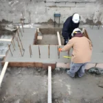 Construction workers leveling concrete foundation.