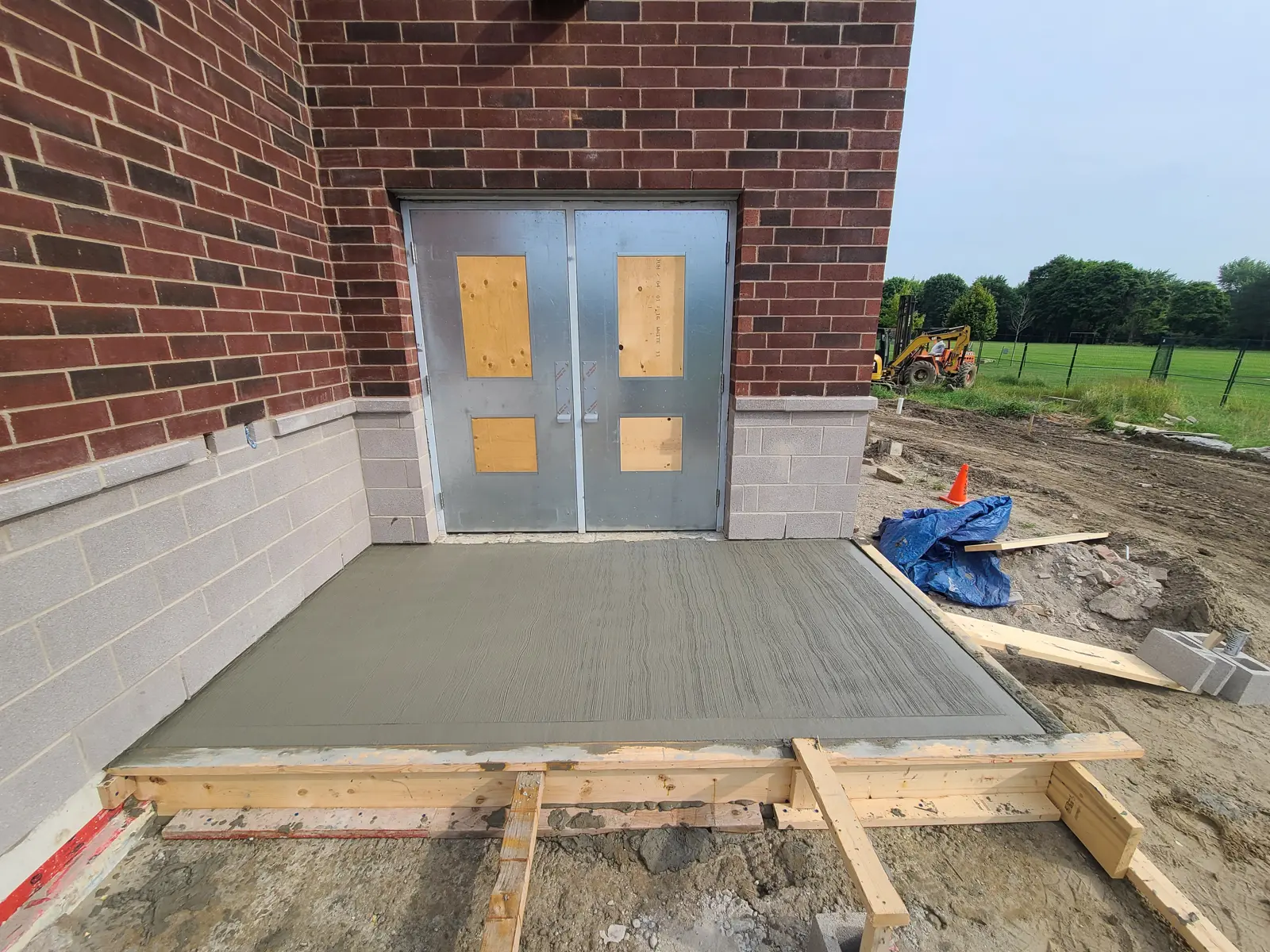 Fresh concrete sidewalk outside building entrance.