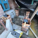 Construction site with concrete forms and muddy ground.