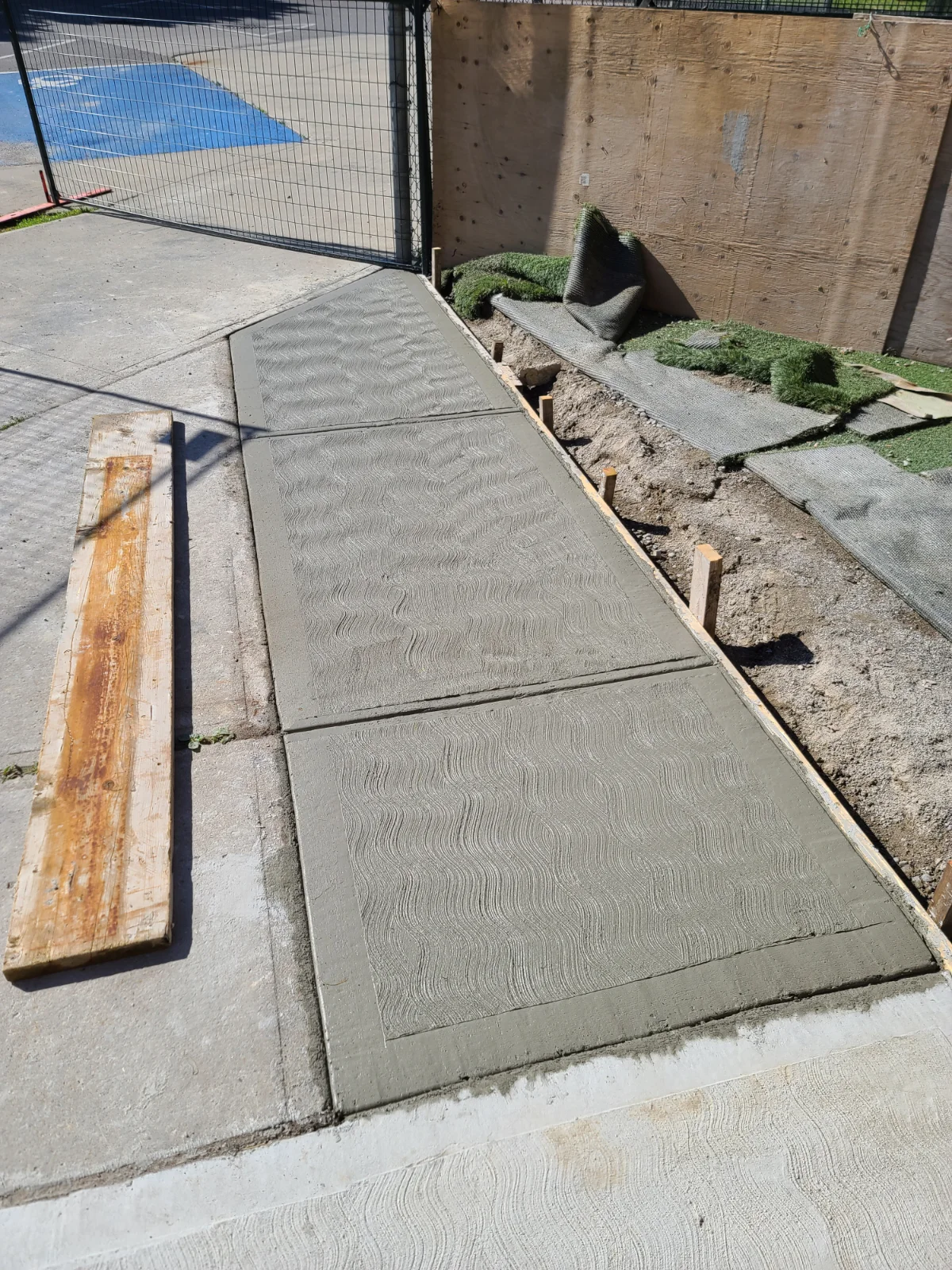 Freshly poured concrete sidewalk near construction site.