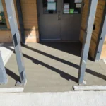 Freshly poured concrete entrance with metal beams.