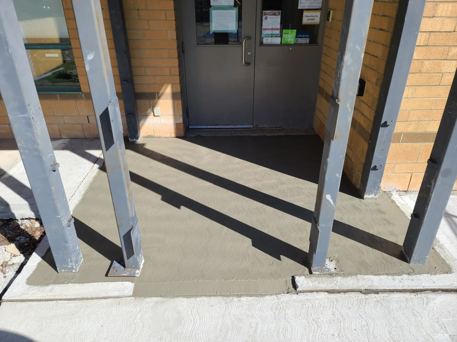 Freshly poured concrete entrance with metal beams.