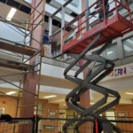 Construction workers on scaffolding inside a building.