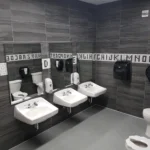 Clean, modern public restroom with sinks and toilets.
