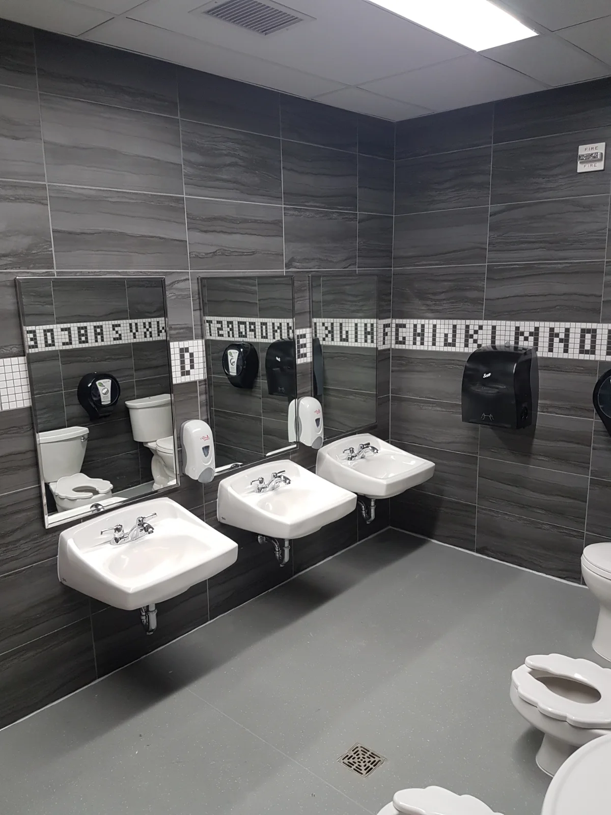 Clean, modern public restroom with sinks and toilets.