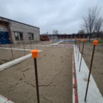 Construction site with rebar and sand foundation.