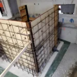 Concrete wall formwork under construction in a building.