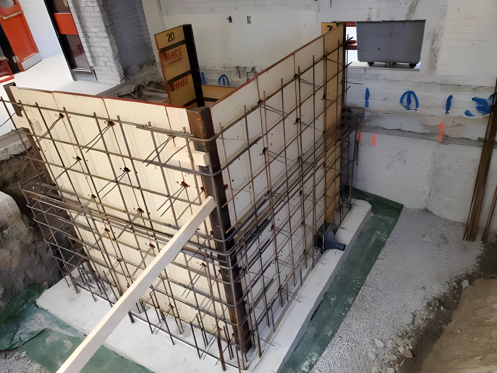 Concrete wall formwork under construction in a building.