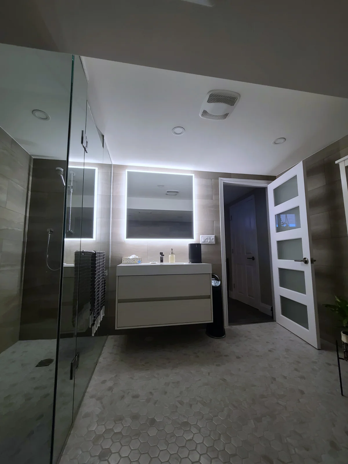 Modern bathroom with illuminated mirror and glass shower