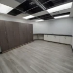 Empty room with wooden cabinets and ceiling tiles.