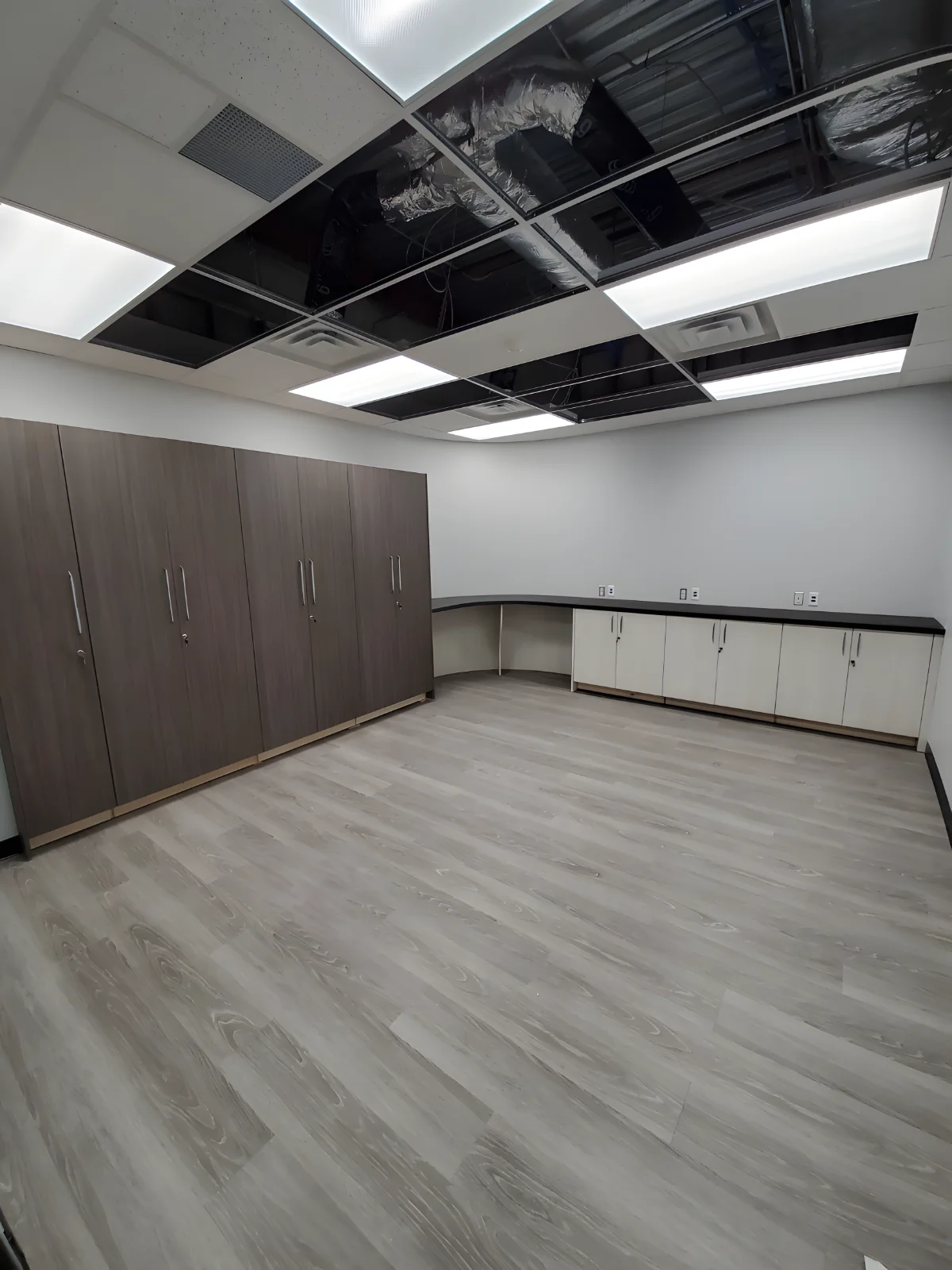 Empty room with wooden cabinets and ceiling tiles.