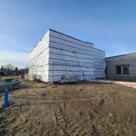 Building under construction with tarp covering exterior.
