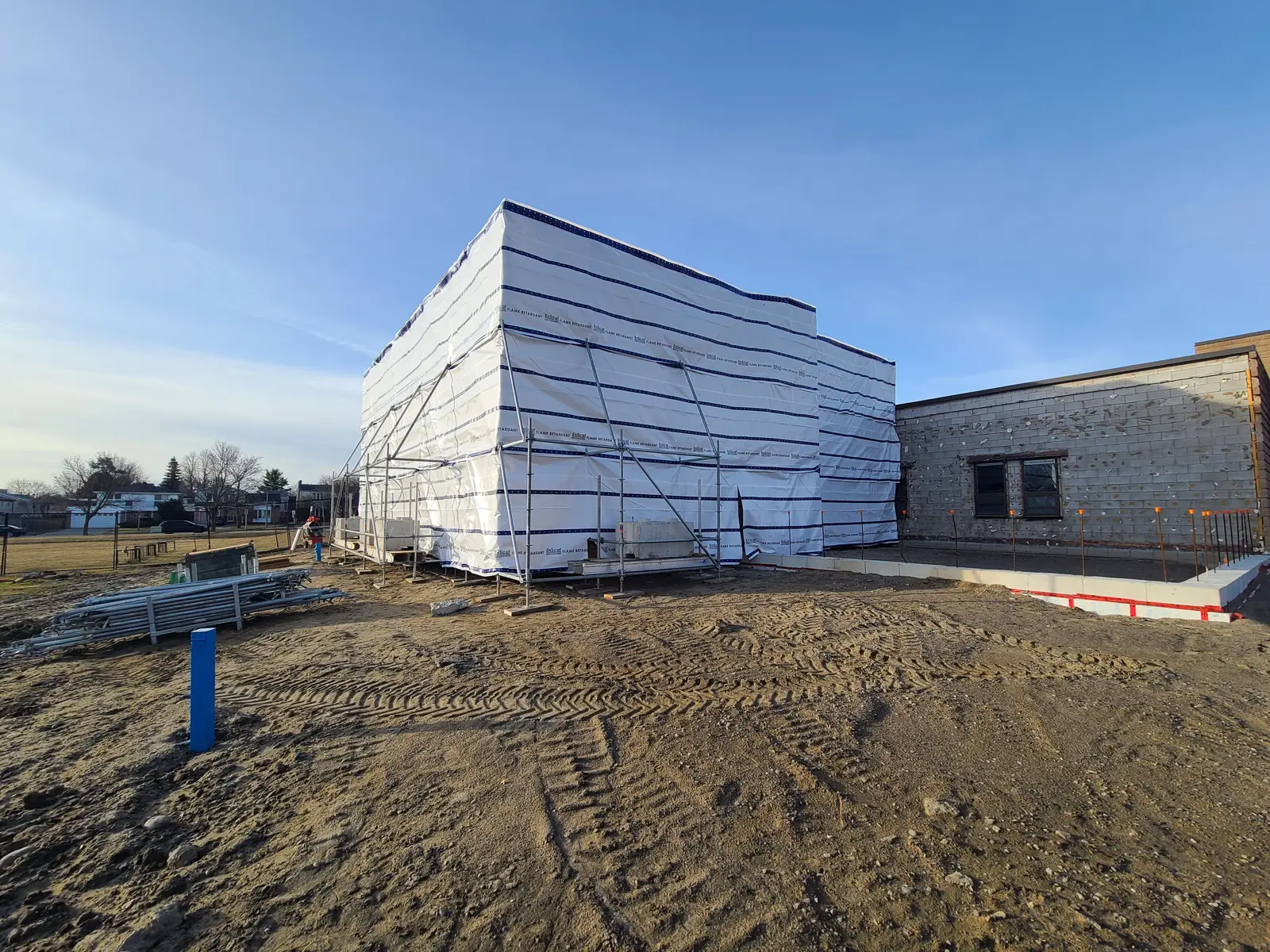 Building under construction with tarp covering exterior.