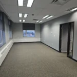 Empty office room with windows and lighting.