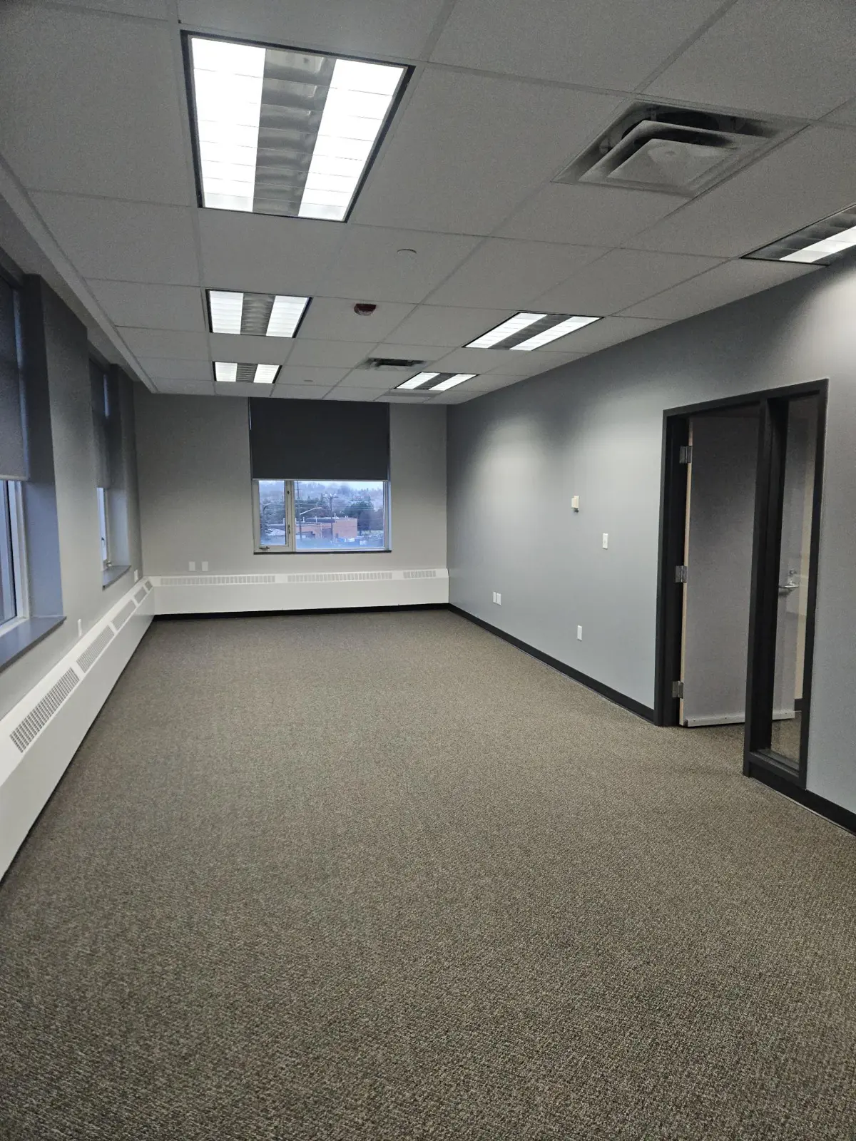 Empty office room with windows and lighting.