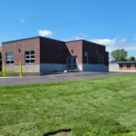 New brick building with green lawn and blue sky.