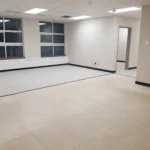 Empty room with tiled floor and large windows.