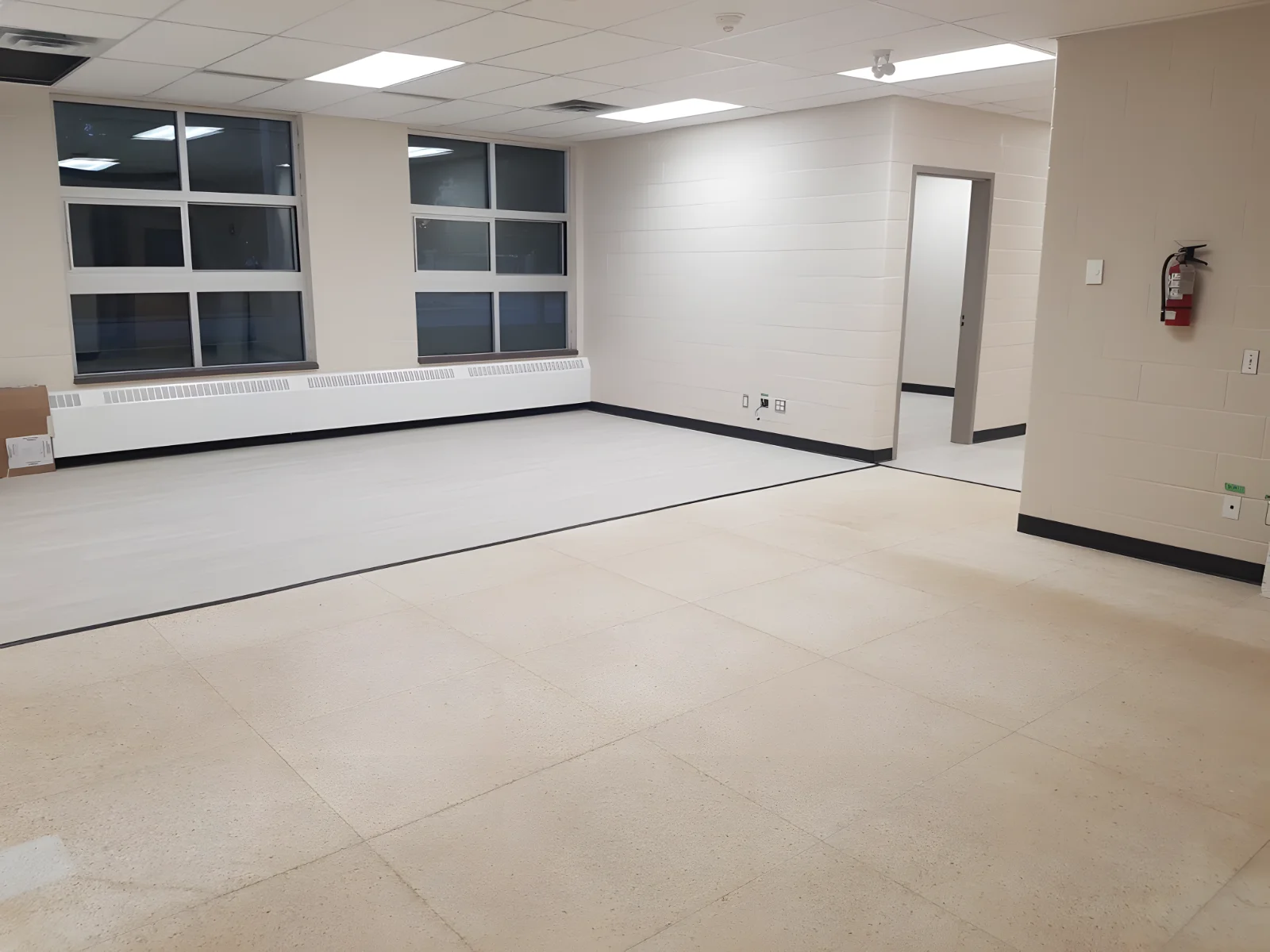 Empty room with tiled floor and large windows.