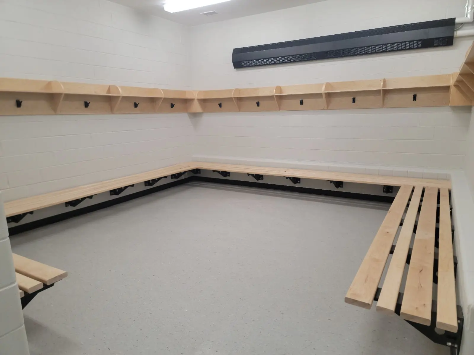 Empty locker room with wooden benches and hooks.