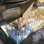 Concrete foundation with exposed rebar framework on site.