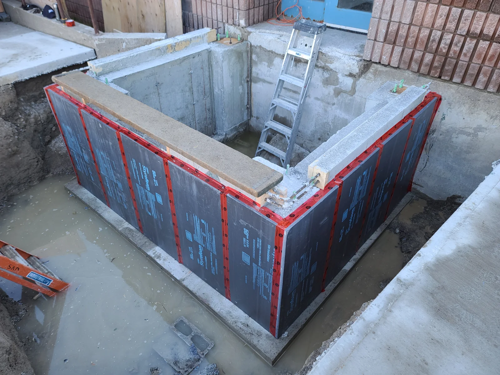 Construction site with foundation and ladder.