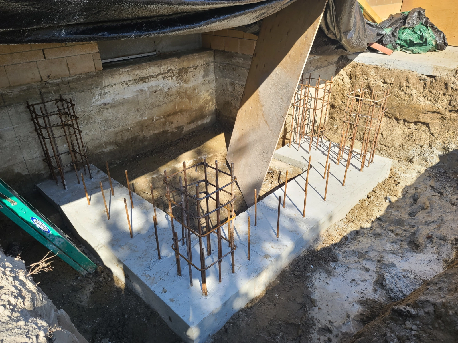 Concrete foundation with exposed rebar framework on site.
