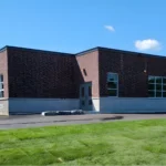 Brick building with large windows and grass lawn.