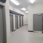 Industrial corridor with metal doors and fluorescent lights.
