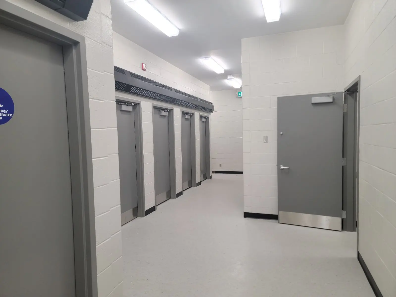 Industrial corridor with metal doors and fluorescent lights.