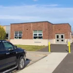 Single-story brick building with parked black truck in foreground.