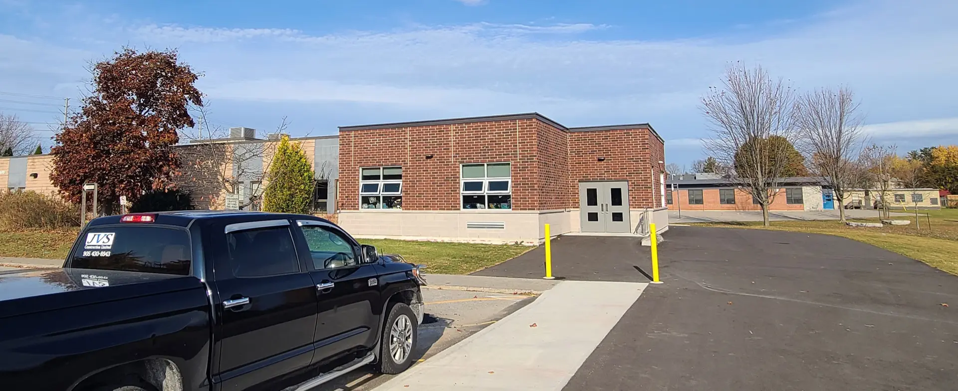 Single-story brick building with parked black truck in foreground.