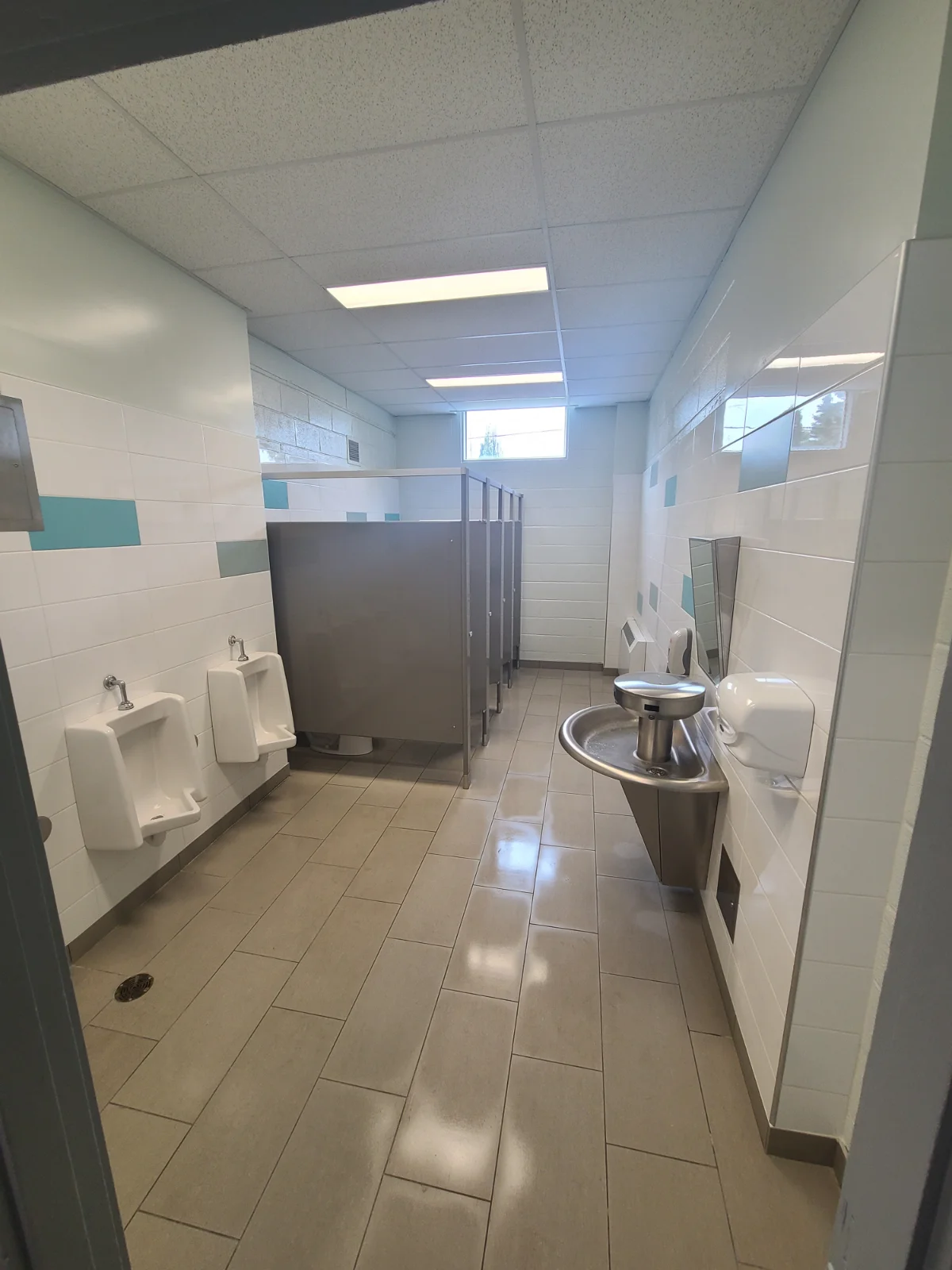 Empty public restroom with stalls and sinks.