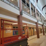 School hallway under renovation with lift equipment.