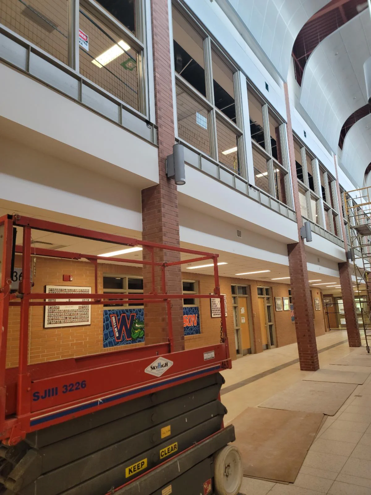 School hallway under renovation with lift equipment.
