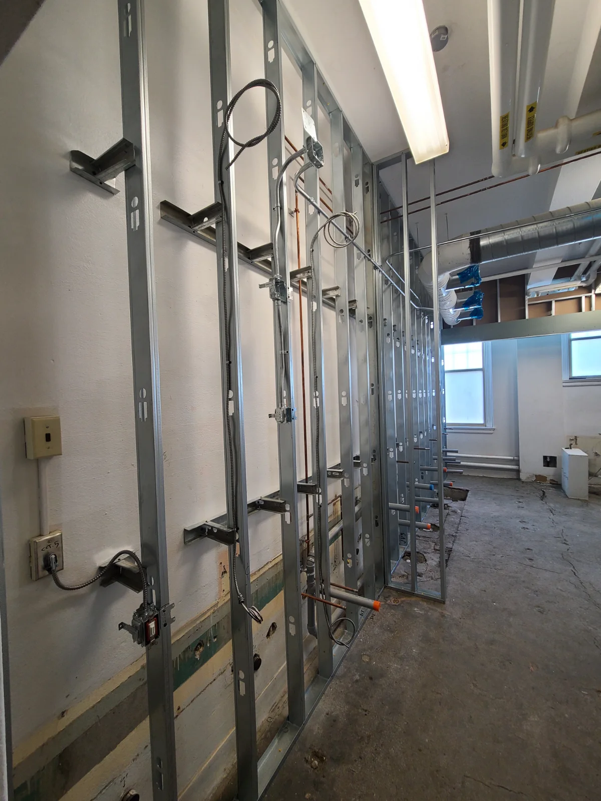 Unfinished wall with exposed metal studs and wiring.